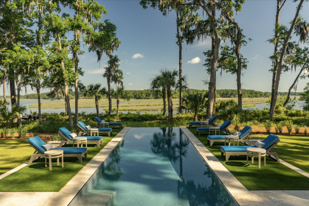 Backyard pool overlooking the marsh with lounge chairs and palm trees